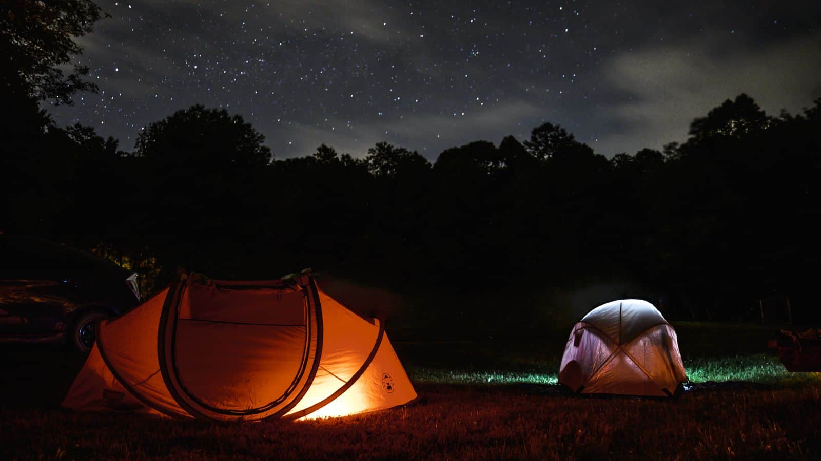 A tent glowing at a forest campsite at night