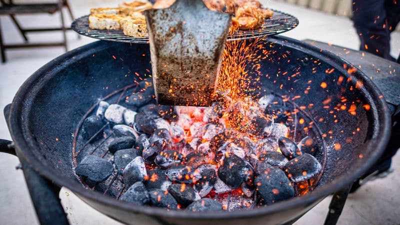Meat grilling over glowing coals with smoke